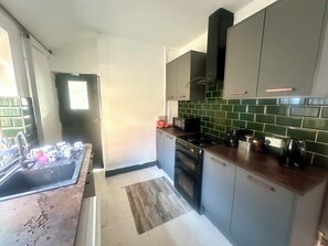 Eine Küche mit Herd, Backofen und Mikrowelle. Ein Fenster bietet Blick ins Freie.