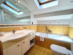 A bathroom with a skylight, a sink, a bathtub, and a toilet. - 2 Bedrooms Commandant André 41 by Viva Riviera (Cannes)