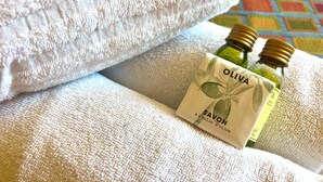 Une bouteille d’huile d’olive et une serviette sur une surface texturée.