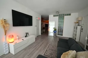 A modern living room with a flat-screen TV, a white console table, a dark-colored sofa, and a patterned rug. - City-Chic at Centennial Hill downtown (Atlanta)