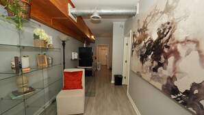 A modern hallway with a glass display unit, a white sofa with a red cushion, and a large abstract painting on the wall. - City-Chic at Centennial Hill downtown (Atlanta)