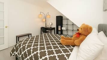 A bedroom with a bed, a desk, a chair, a lamp, a teddy bear, and a wardrobe.
