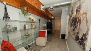 A modern living room with glass shelves, a red cushion, a white chair, and a large abstract painting. - City-Chic at Centennial Hill downtown (Atlanta)