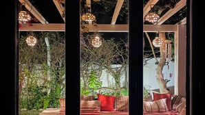 Quarto com sofá, almofada vermelha e luminárias pendentes esféricas.