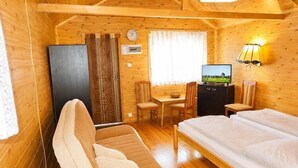 A wooden cabin room with a bed, a desk, a chair, a television, and a clock on the wall. - Cottage for 4 people, Wapnica (Wapnica)