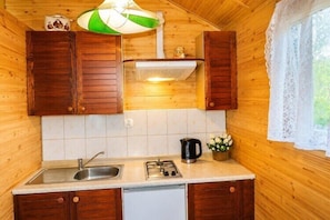 Interior d'una cabana de fusta amb zona de cuina, incloent-hi un rentapeus, fogó i armaris.