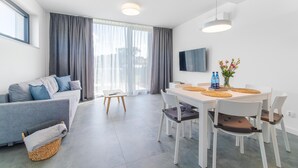 A modern living room with a sofa, dining table, chairs, and a TV. - New holiday homes, Dziwnow (Dziwnów)
