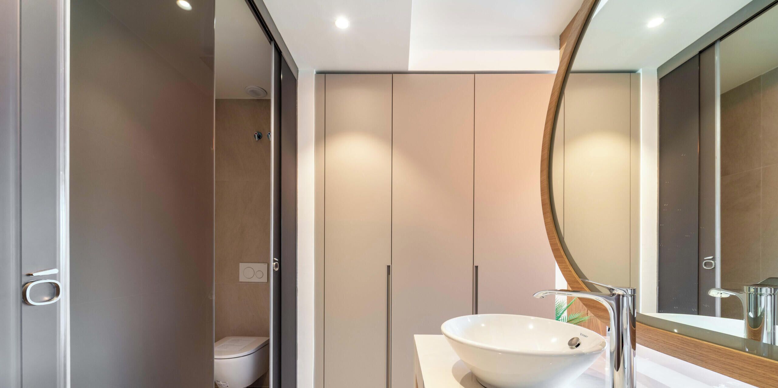 Un baño moderno con inodoro, lavamanos y espejo.