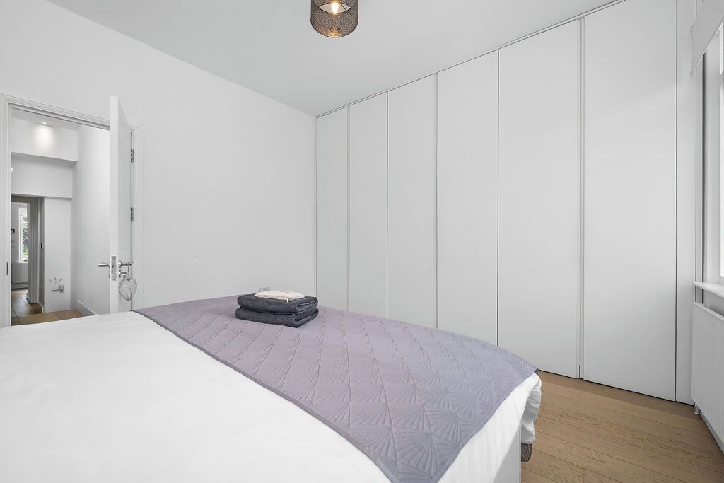 Un dormitorio con una cama, un armario y una puerta que da a otra habitación.