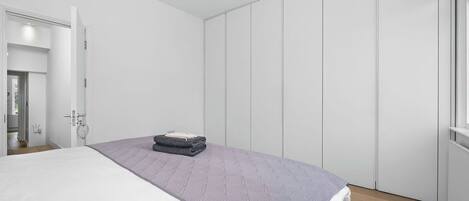 Un dormitorio con una cama, un armario y una puerta que da a otra habitación.