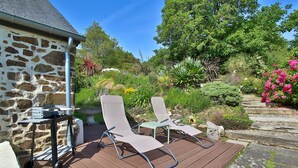 Une terrasse avec deux chaises longues, une petite table et un bâtiment en pierre.
