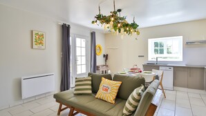 Un salon comprenant un canapé, une table à manger, un coin cuisine et une fenêtre avec des rideaux.