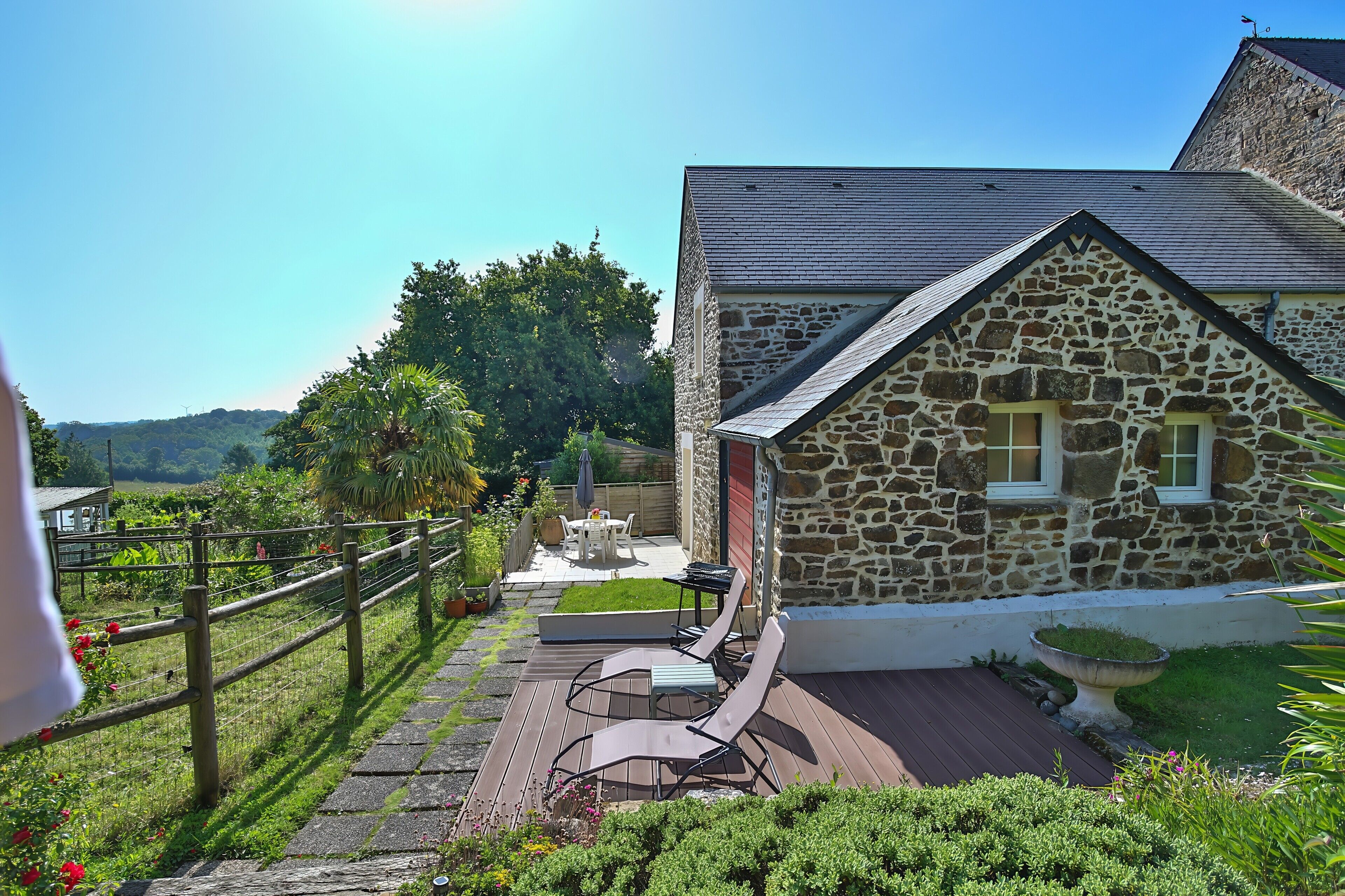 Un bâtiment en pierre doté d’une terrasse, de mobilier d’extérieur et offrant une vue sur le paysage.