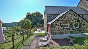 Un bâtiment en pierre doté d’une terrasse, de mobilier d’extérieur et offrant une vue sur le paysage.