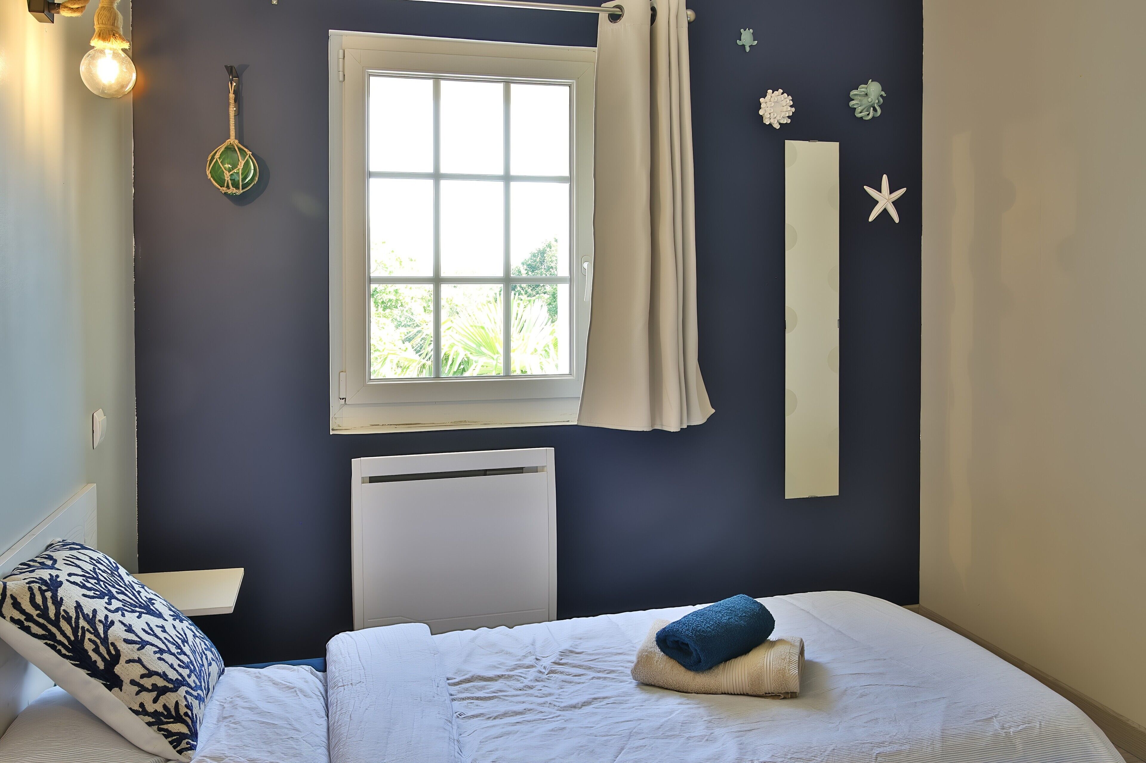 A bedroom with a bed, a window, a radiator, and wall decorations.