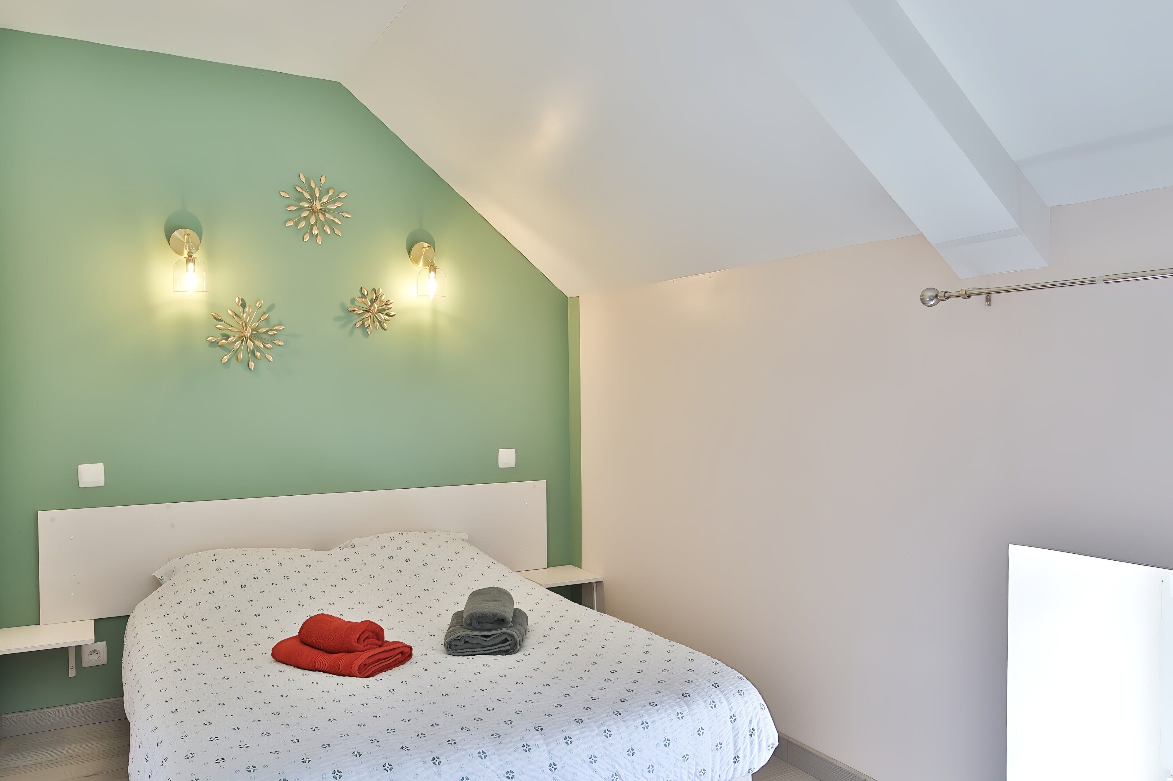 Ein Schlafzimmer mit einem Bett, einem Nachttisch, einer Wandleuchte und einer Deckenlampe.