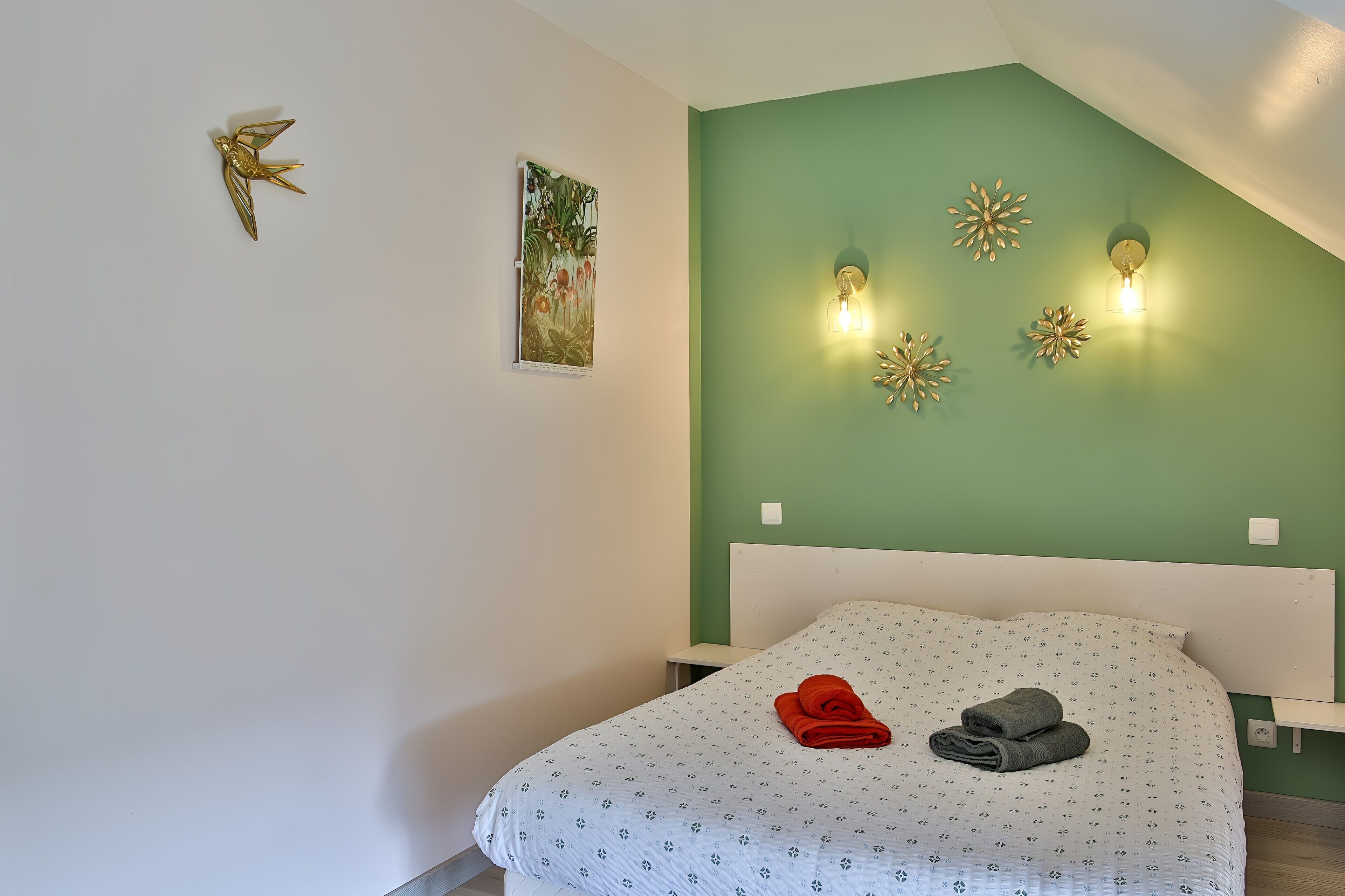 Un dormitorio con una cama, un aplique de pared y un adorno mural.