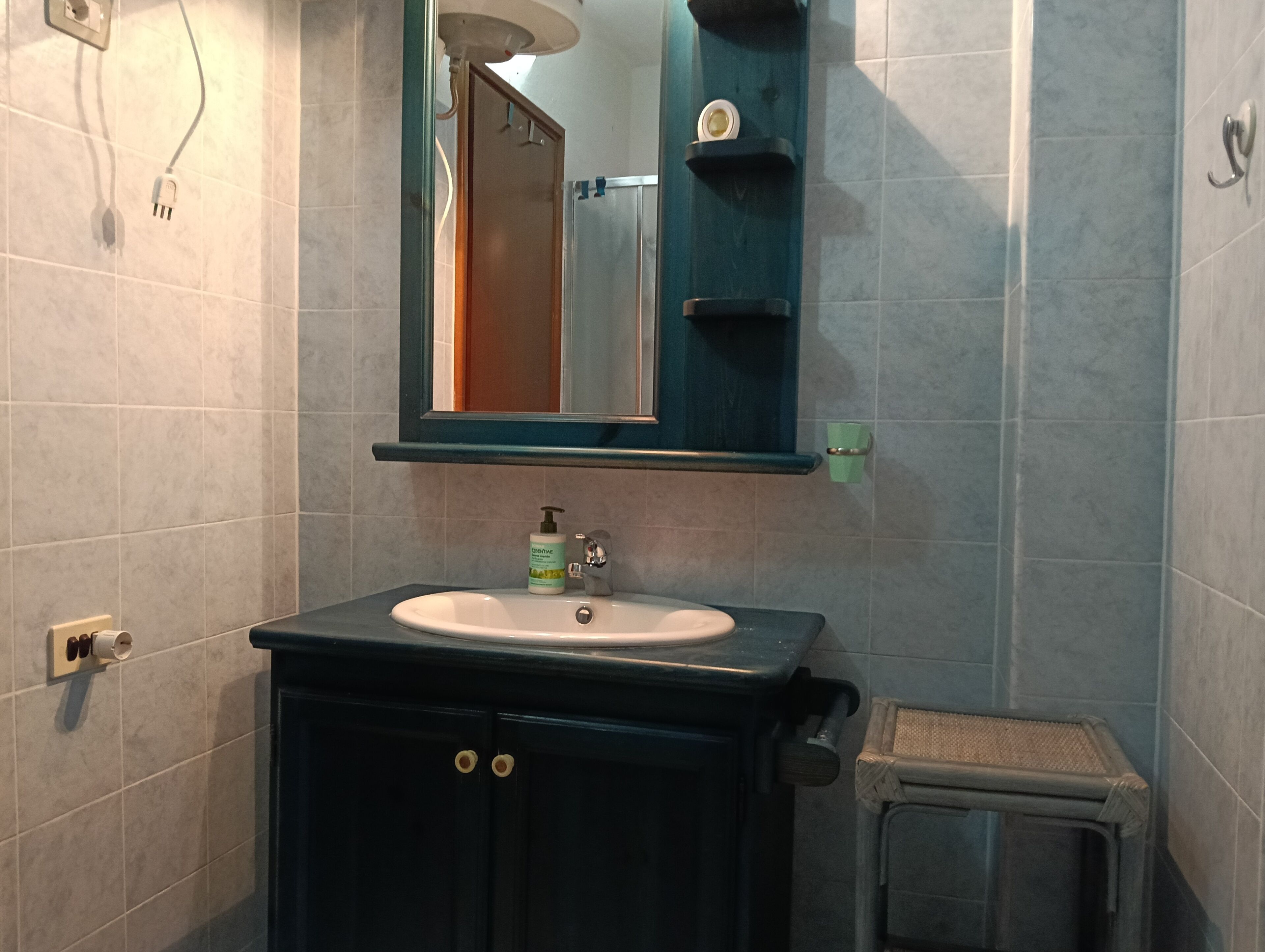 Un baño con lavamanos, espejo y un pequeño taburete.