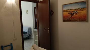 Une pièce comprenant un lit, une chaise, un tableau et une porte donnant sur une autre pièce.