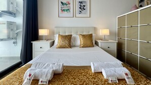 Ein Hotelzimmer mit einem Bett, zwei Nachttischen, einem Kleiderschrank und zwei gerahmten Kunstwerken an der Wand.