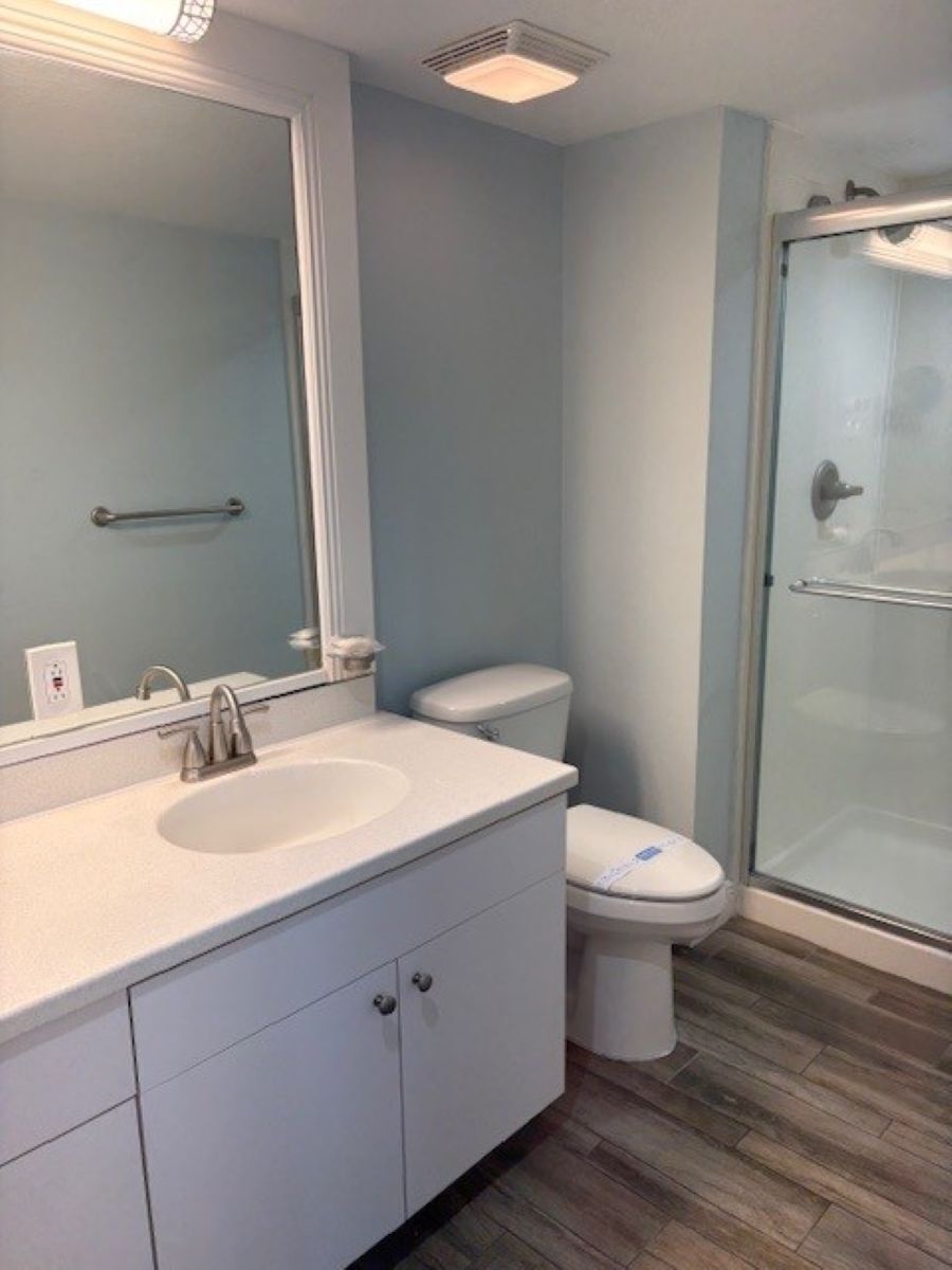 A bathroom with a sink, mirror, toilet, and glass shower enclosure.
