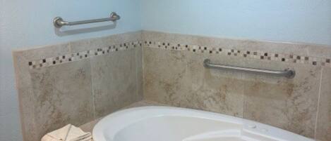 A bathroom with a bathtub, grab bars, and a 'Welcome' sign.