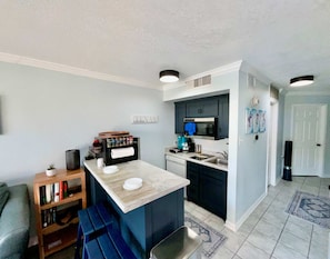 Una cocina compacta con una isla central, un microondas y un lavamanos.