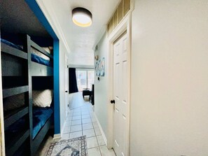 Un couloir avec une porte blanche, un mur bleu et un tapis à motifs.