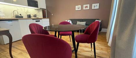 Una cocina moderna con armarios blancos, un lavavajillas Bosch y un comedor con una mesa redonda y sillas rojas.