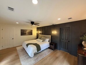 A bedroom with a bed, ceiling fan, recessed lighting, and a dark wall paneling. - Lakefront Escape in Hot Springs 2BR/2BA, Hot Tub, Fireplace & Boat Slips (Hot Springs National Park)