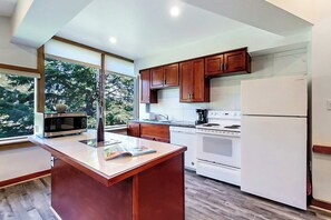 A modern kitchen with wooden cabinets, a white refrigerator, a stove, and a microwave.