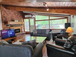 A living room with a fireplace, a television, and a large window.