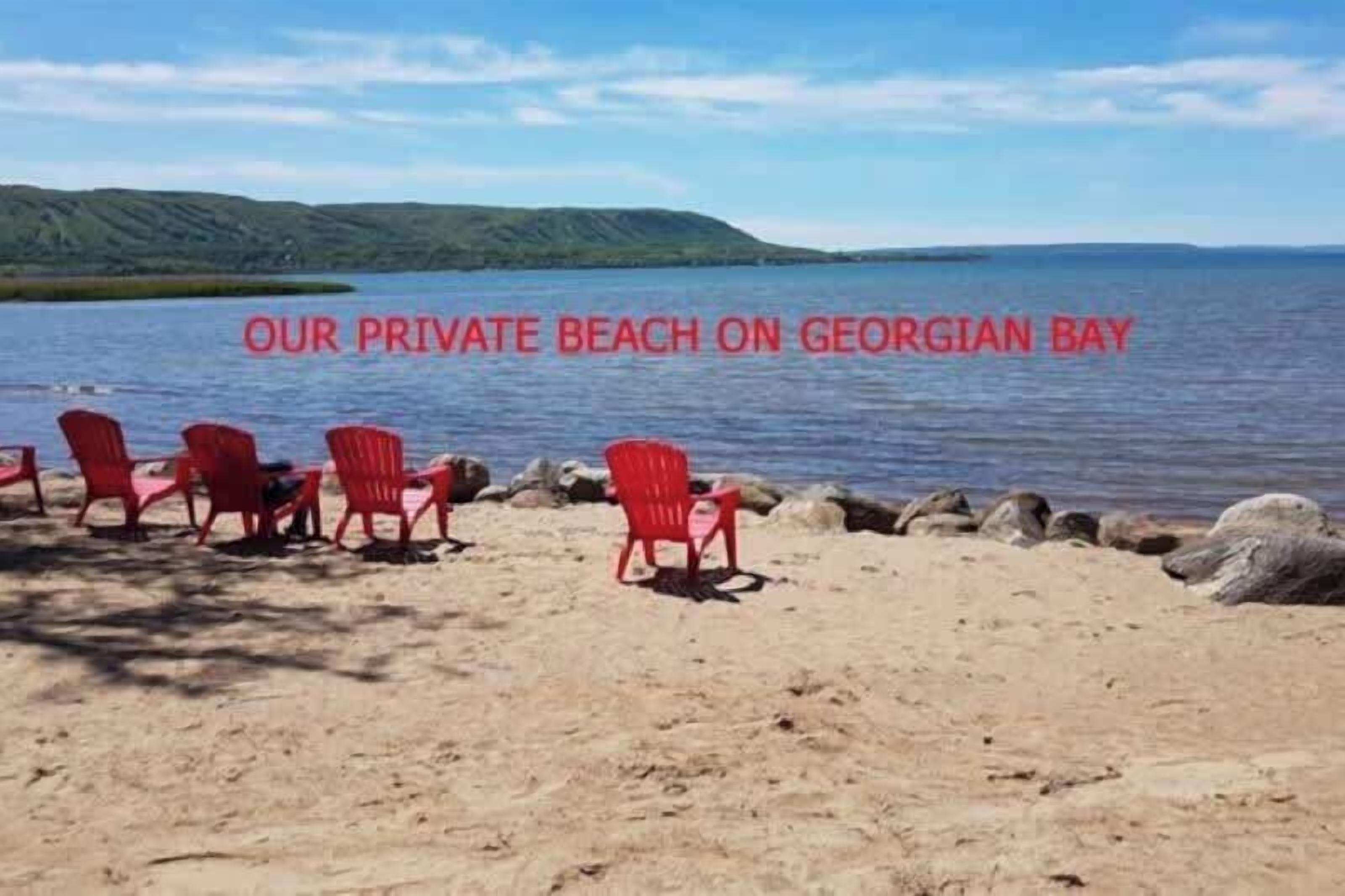 A private beach with red chairs and a view of Georgian Bay.