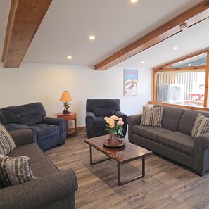 A living room with two sofas, a coffee table with a vase, a lamp, and a poster on the wall.