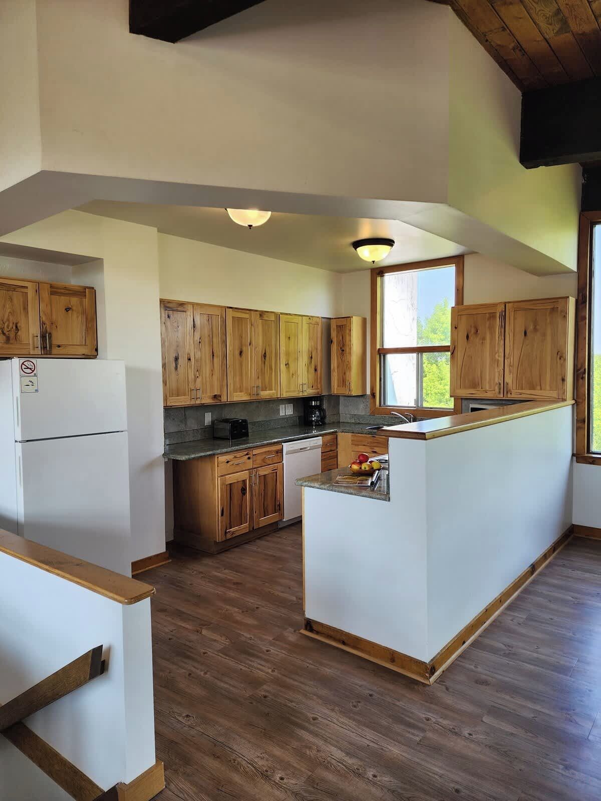 A kitchen with wooden cabinets, a central island, and a large window.