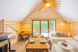 Un chalet confortable avec un intérieur en bois, un coin repas avec une table et des chaises, un canapé et un luminaire au plafond.