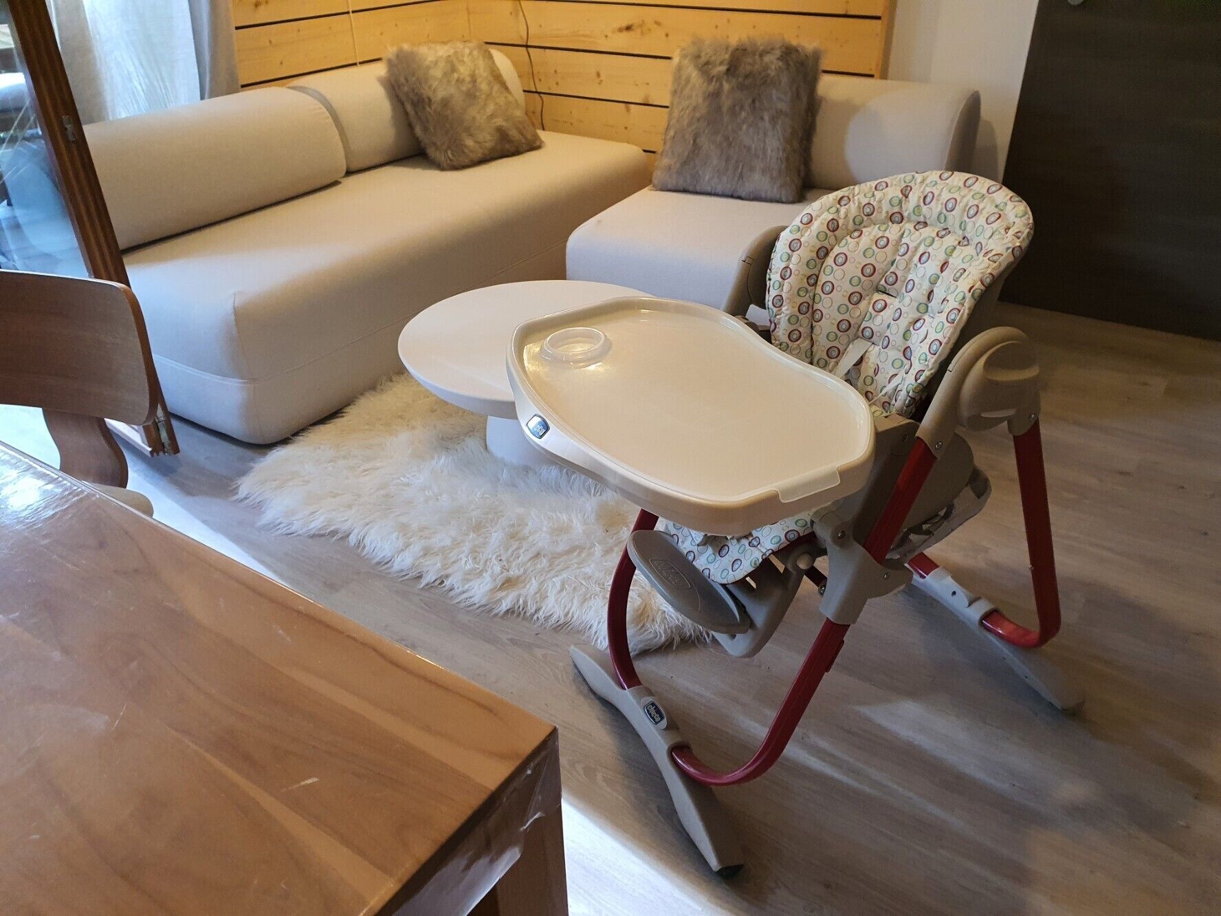Un salon moderne avec une chaise haute, un canapé et une table en bois.