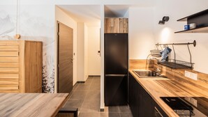 A modern kitchen with a wooden countertop, a black refrigerator, and a sink. - “L’aubier des Bauges” Apartment: Mountain View, Private Terrace, Wi-Fi (Les Déserts)