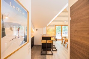Eine moderne Küche mit Holzausbau, ein Essbereich mit Tisch und Stühlen sowie ein großes gerahmtes Bild an der Wand.