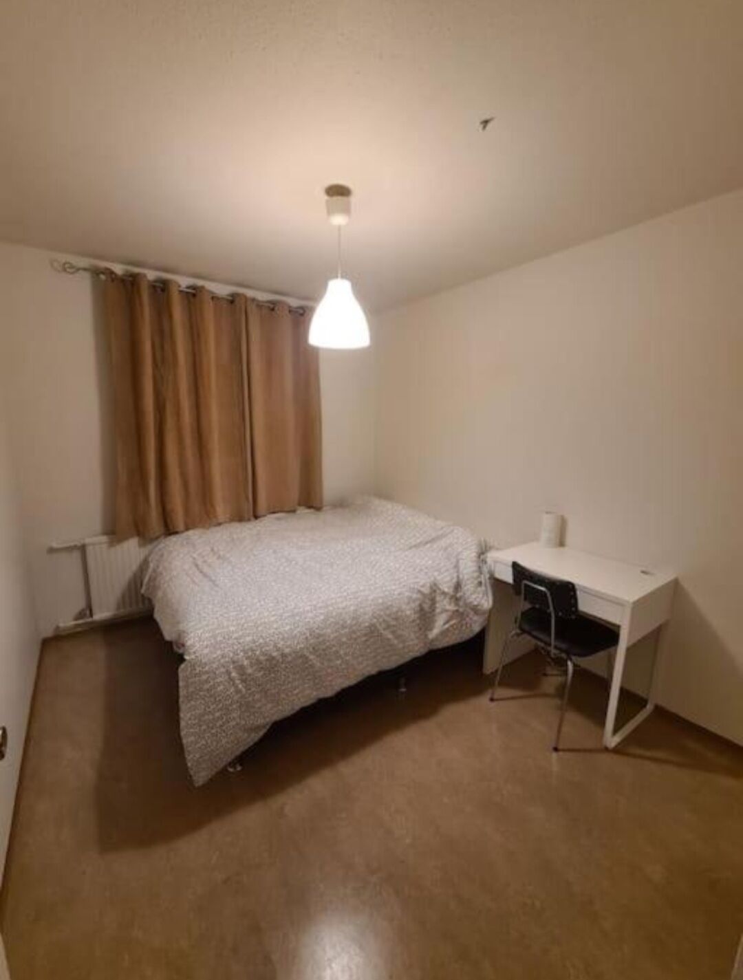 Ein Schlafzimmer mit einem Bett, einem Schreibtisch und einer Hängelampe.