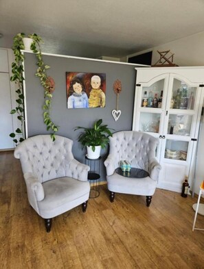 A room with two tufted armchairs, a potted plant, a cabinet with glass doors, and a painting on the wall. - Serene 3-bedroom apartment in Reykjavík perfect for your getaway (Reykjavík)