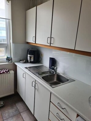 A small kitchenette with white cabinets, a stainless steel sink, a coffee maker, and a kettle. - Serene 3-bedroom apartment in Reykjavík perfect for your getaway (Reykjavík)