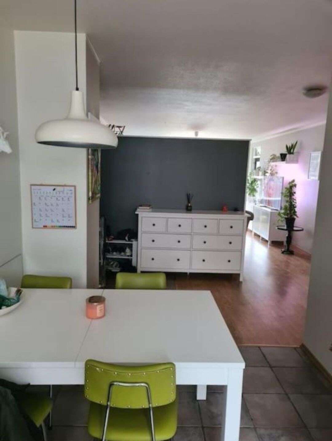 A dining area with a white table and chairs, a white cabinet, and a ceiling light.