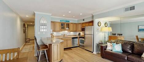 A modern kitchen with wooden cabinets, a central island, and a dining area with a bench.