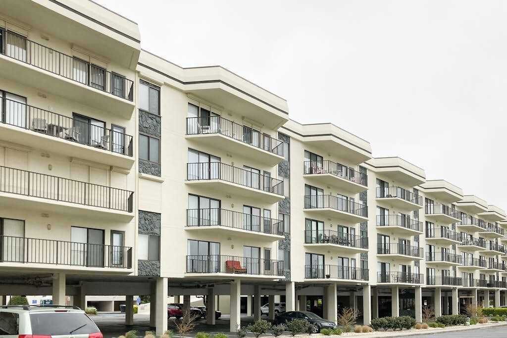 Een hotel met meerdere verdiepingen, balkons, een parkeerplaats en een modern architectonisch ontwerp.