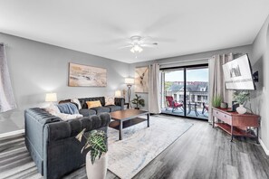 A modern living room with a sofa, coffee table, and a view of the city through large windows. - All Newly Remodeled! 3 Min To Strip! Two Pools, Hot Tub, Sauna (Branson)