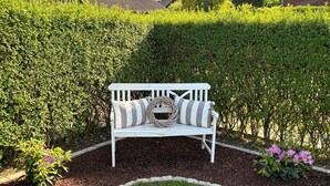A white bench with striped cushions in a landscaped garden. - Leling Holiday Apartment – Relaxation with a Wellness View (Havixbeck)