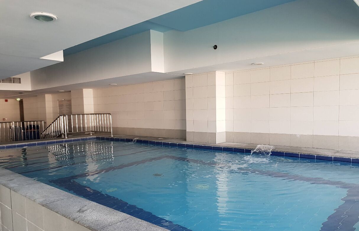 Ein Hallenbad mit gefliesten Wänden und blauem Wasser.