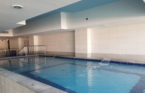 Ein Hallenbad mit gefliesten Wänden und blauem Wasser.