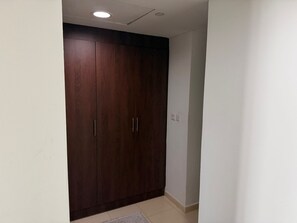 Ein Zimmer mit einem großen Holzschrank, einem Lichtschalter und einem Fliesenboden.